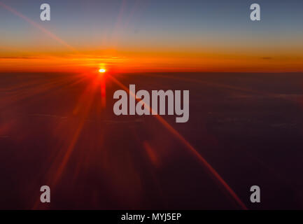 Vivido arancione tramonto o l'alba sopra le nuvole visto da un aereo in volo in un meteo e viaggi sfondo a tema Foto Stock