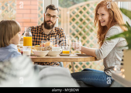 Famiglia moderna di consumare la colazione in un pergolato vicino ad un giardino Foto Stock