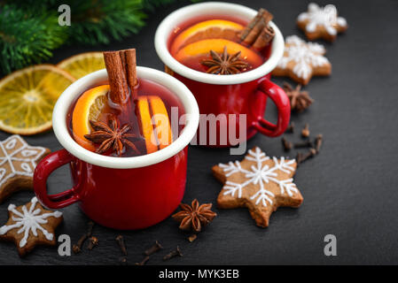Vin brulé in metallo tazze con biscotti e arance essiccate su sfondo di legno Foto Stock