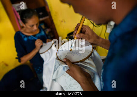 Un uomo di Salvadoran richiama la cera su un tessuto tinto con un naturale blu indaco successivamente in un laboratorio di abbigliamento a Santiago Nonualco, El Salvador. Foto Stock