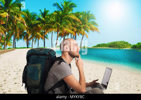 Piani esplora un nuovo viaggio su una spiaggia tropicale con il suo computer portatile Foto Stock