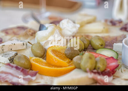 Deliziosi snack italiani come olive, ricotta, formaggio, prosciutto, fragole, arancione Foto Stock