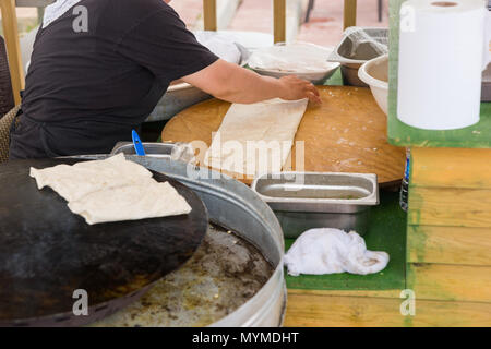 Lo Chef rendendo gozleme flatbread in Anatolia, Turchia e crisping su di una piastra in un vicino la vista ritagliata Foto Stock