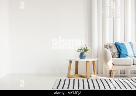 Cuscino blu sul divano bianco e rose in vaso blu in living room interior Foto Stock