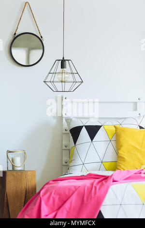 Bianco camera da letto geometrico con lampada industriale, triangolo quilt, specchio rotondo Foto Stock