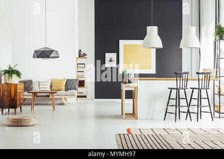 Oro dipinto sul muro nero in camera spaziosa cucina con isola e modellato cuscini sul divano Foto Stock
