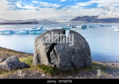 Split Rock e iceberg galleggianti in Jokulsarlon laguna glaciale Vatnajökull Parco Nazionale di Islanda Foto Stock
