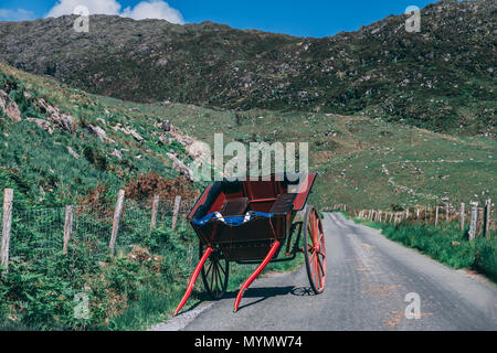 Una carrozza si trova sulla strada panoramica di gap di Dunloe, una stretta mountain pass nella contea di Kerry, Irlanda in una giornata di sole Foto Stock