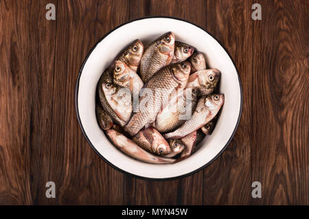 Catture di pesca. Recipiente pieno di carassi su un marrone di sfondo di legno Foto Stock