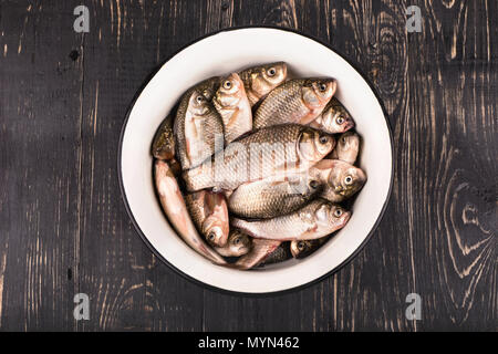 Catture di pesca. Pieno di carassi ciotola di legno scuro dello sfondo Foto Stock