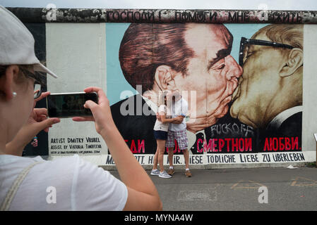 Berlino. Germania. I turisti posano per le foto di fronte una delle restanti sezioni del muro di Berlino all'East Side Gallery. I turisti pongono per ph Foto Stock