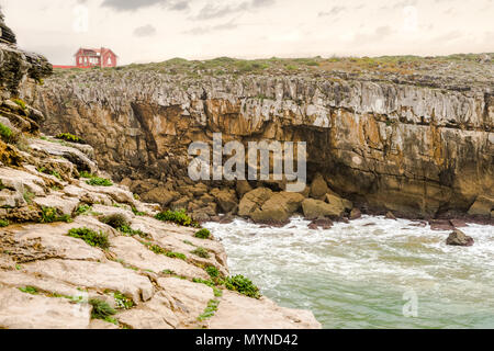 Red casa abbandonata situata alla sommità di una scenografica scogliera con alta marea su una solitaria isola Foto Stock