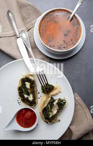 Cena con lo strudel e la Minestra sulla pietra grigia sullo sfondo Foto Stock