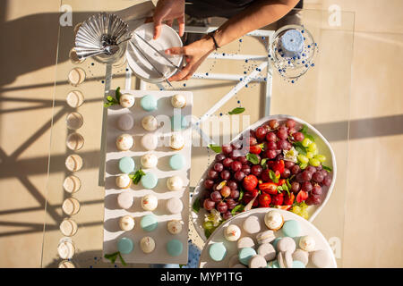 Dolce Tabella di nozze con dolci e fragola, uva sulla parte superiore, frutti. reception. Mani decorare la tavola Foto Stock