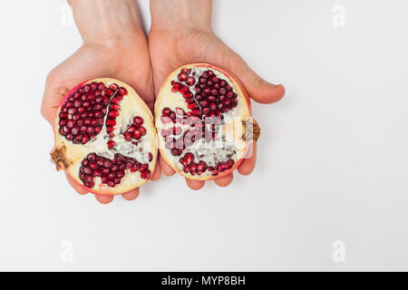 Mano che tiene il melograno isolati su sfondo bianco Foto Stock