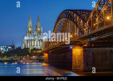La cattedrale di Colonia e il Hohenzollern ponte ferroviario dopo il tramonto Foto Stock
