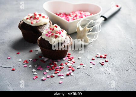 Muffin al cioccolato o i tortini con cuore spruzza. San Valentino la cottura. Messa a fuoco selettiva, tonica immagine. Foto Stock