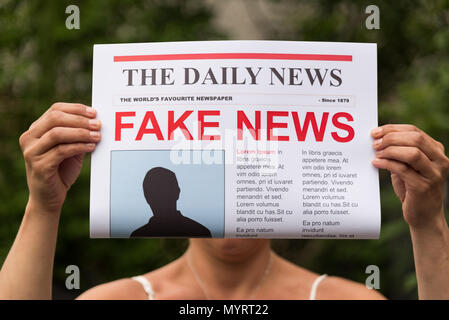 Donna che mantiene un giornale con la headline fake news Foto Stock