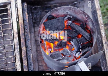 Un motorino di avviamento di camino in uso per ottenere il carbone pronto per il grill in modo più ecologico. Foto Stock