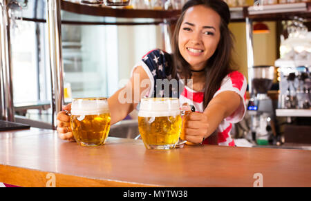 Femmina gioiosa barista è che offre birra Foto Stock