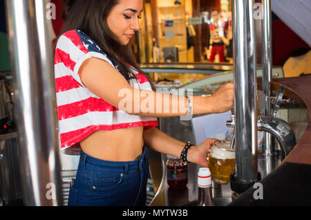 Bella femmina barman è a versare birra da toccare presso il bar Foto Stock