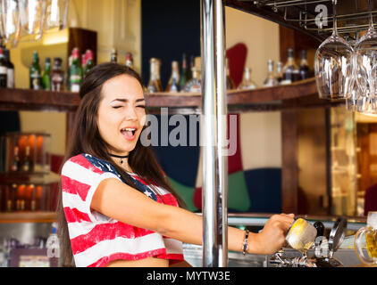 Gioiosa barista si versa la birra da toccare presso il bar Foto Stock