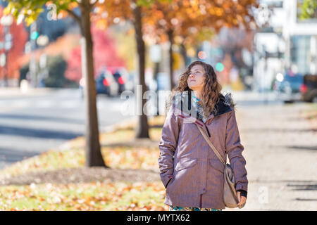 Giovane donna sul marciapiede street a piedi a Washington DC, Stati Uniti d'America Stati Uniti in Vicolo dell oro giallo arancio fogliame di autunno alberi cadono sulla strada durante la s Foto Stock