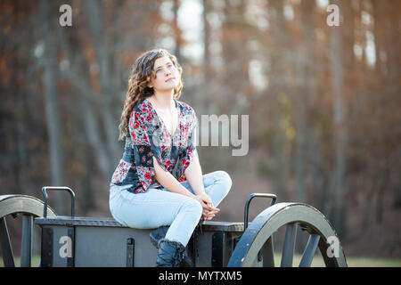 Giovane donna seduta su un vecchio cannone carrello in Manassas National Battlefield Park in Virginia dove Bull Run battaglia è stata combattuta, luce solare cercando dre Foto Stock