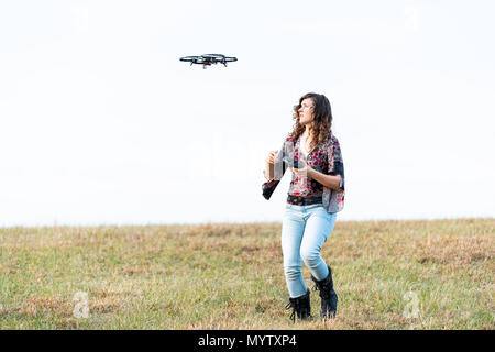 Giovane donna focalizzato cercando di controllare la telecamera video drone in autunno o cadere con scarponi nel parco in Virginia campagna campo aperto hill Foto Stock