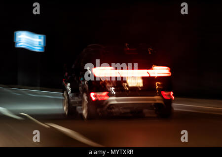Abstract closeup di una vettura in movimento nella notte buia sera variopinti colori, luci di strada, rosso forma di frenatura Foto Stock