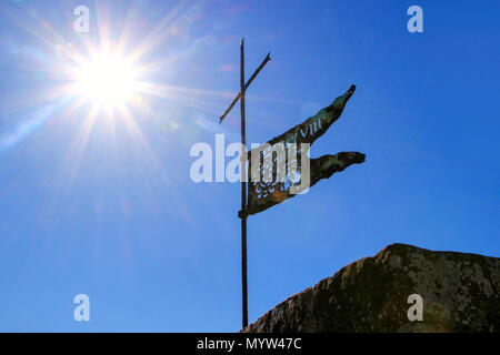 Bandiera di metallo sulla parte superiore della Fortezza di Montalcino la torre contro il cielo blu con sunburst, Val d'Orcia, Toscana, Italia. La fortezza fu costruita nel 1361 in cima th Foto Stock