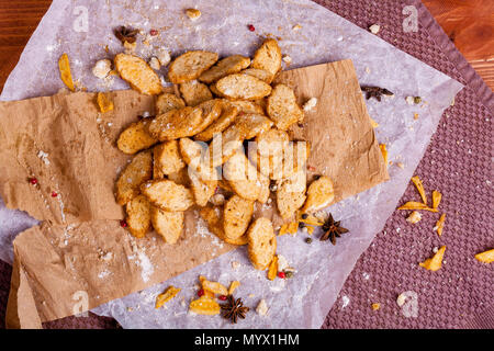 Croccanti e profumati bianchi sono i crostini fritti e giacente su un sfondo di legno. Un po' di spezie è stato aggiunto ad essa e di essa risiede anche su carta kraft. G Foto Stock