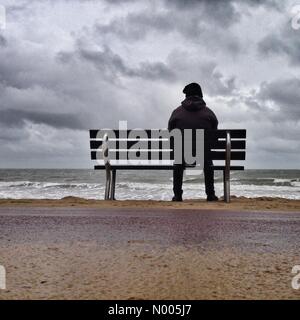 Persona seduta su una panchina da soli a Bournemouth Beach Foto Stock