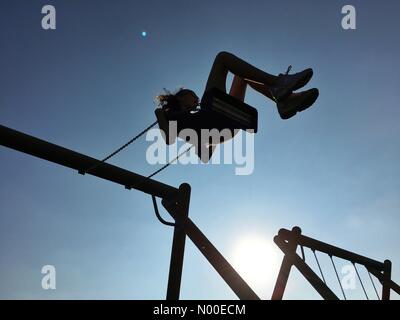 Regno Unito: Meteo sunny serata in Adlington, Lancashire. Giovane ragazza si raffredda dopo una calda giornata facendo oscillare contro il blu limpido cielo di sera. Foto Stock