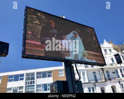 Uno schermo gigante sul lungomare a Bexhill sul mare in East Sussex, Regno Unito mostra il principe Harry e Meghan Markle's Royal Wedding. Foto Stock