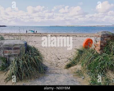 Anglesey, Regno Unito. Il 27 ottobre 2018. Corsi di Kite surf di essere trasportati attraverso bordo d'acqua sulla spiaggia di Rhosneigr, Anglesey, Galles del Nord, Regno Unito, su di un soleggiato ma blustery giorno Credito: Charlotte Machin/StockimoNews/Alamy Live News Foto Stock