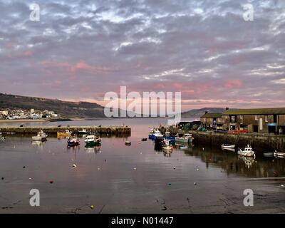 Lyme Regis, Dorset, Regno Unito. 7 gennaio 2021. UK Weather: Le nuvole sopra il Cobb Harbour brillano rosa mentre il sole del tardo pomeriggio si riflette al tramonto alla fine di un freddo giorno di gennaio. Credit: Celia McMahon/StockimoNews/Alamy Live News Foto Stock