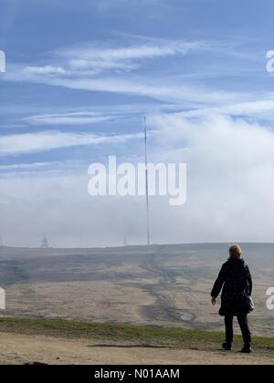 Meteo nel Regno Unito: Soleggiato a Rivington, Lancashire. Una domenica di Pasqua soleggiata a Rivington vicino Chorley nel Lancashire. Una mattinata ventosa in cima a Rivington Pike con una donna che cammina e l'albero TV di Winter Hill. Foto Stock