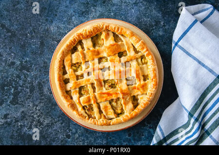 In casa giovani torta cavolo dalla pasta sfoglia servita su una piastra. La pietra blu sullo sfondo. Foto Stock