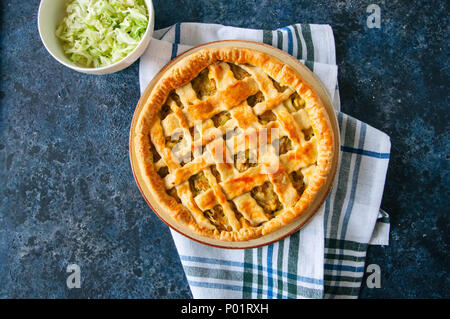 In casa giovani torta cavolo dalla pasta sfoglia servita su una piastra. La pietra blu sullo sfondo. Foto Stock