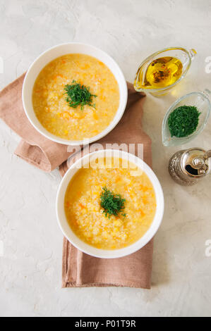 Lenticchia e zuppa di bulgur purea in una ciotola bianco su una pietra bianca dello sfondo. Foto Stock