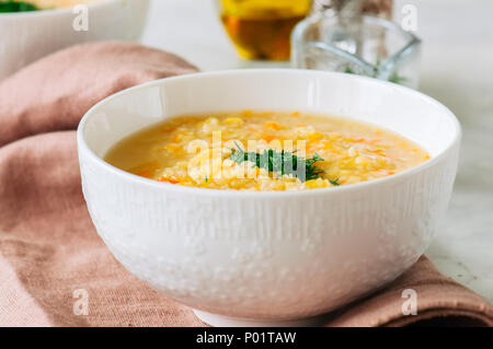 Lenticchia e zuppa di bulgur purea in una ciotola bianco su una pietra bianca dello sfondo. Foto Stock