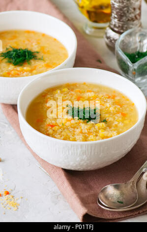 Lenticchia e zuppa di bulgur purea in una ciotola bianco su una pietra bianca dello sfondo. Foto Stock