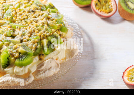 Meringa Pavlova con panna montata e fresche kiwi e frutto della passione, fuoco selettivo. Foto Stock