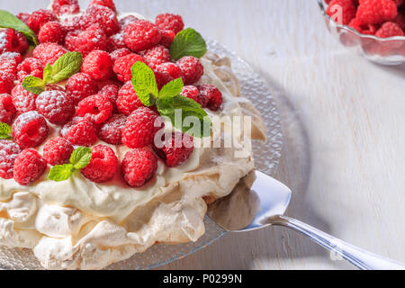 Meringa Pavlova con panna montata e lamponi freschi, il fuoco selettivo. Foto Stock
