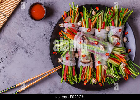 Involtini primavera con verdure e funghi shiitake su una piastra, vista dall'alto. Foto Stock