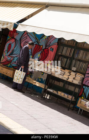 Uomo al di fuori di negozi di seconda mano book shop in stallo, Atene, Grecia. Foto Stock