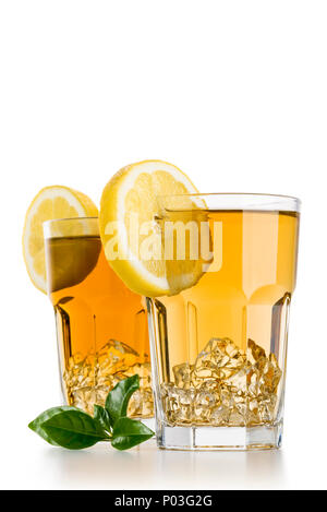 Due bicchieri piena di ghiaccio tè con fette di limone e foglie di tè su sfondo bianco Foto Stock