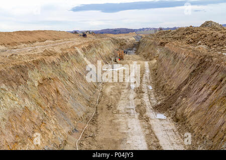 Sito in costruzione tra una grande trincea con un sacco di terra e terriccio Foto Stock