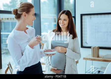 Felice giovane donna mantenendo le mani su addome Foto Stock